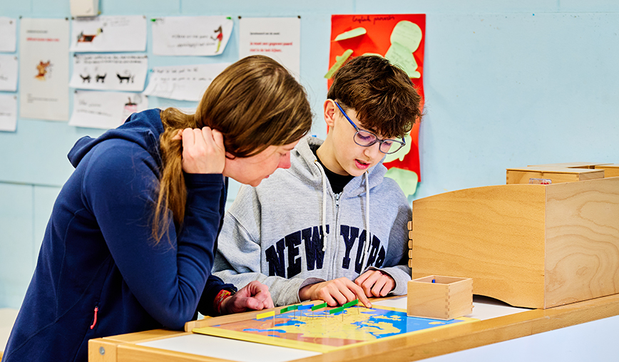 Twee leerlingen werken samen aan een aardrijkskunde project dat op een kast in de klas ligt